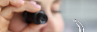 Close-up of jeweller examine polished diamond through magnifying glass, diamond jewellery under grading, look through loupe. Jewelry production concept