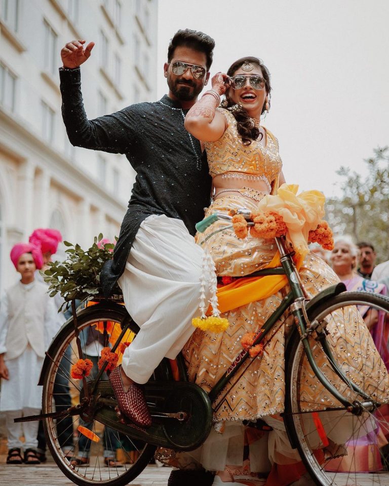 bicycle pose - haldi poses for bride and groom